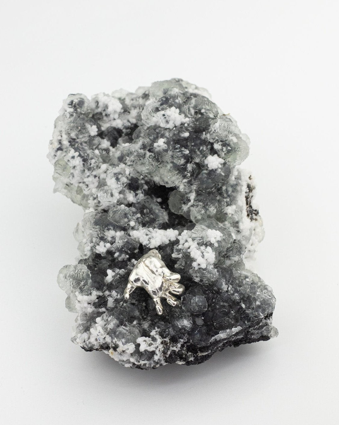 Sterling 925 silver pendant of Rodin's sculpture 'Clenched Hand,' placed on a textured black and white mineral crystal backdrop.