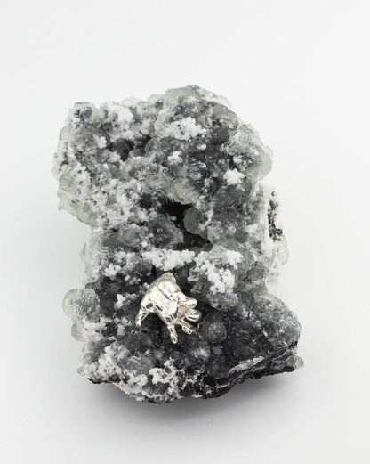 Sterling 925 silver pendant of Rodin's sculpture 'Clenched Hand,' placed on a textured black and white mineral crystal backdrop.