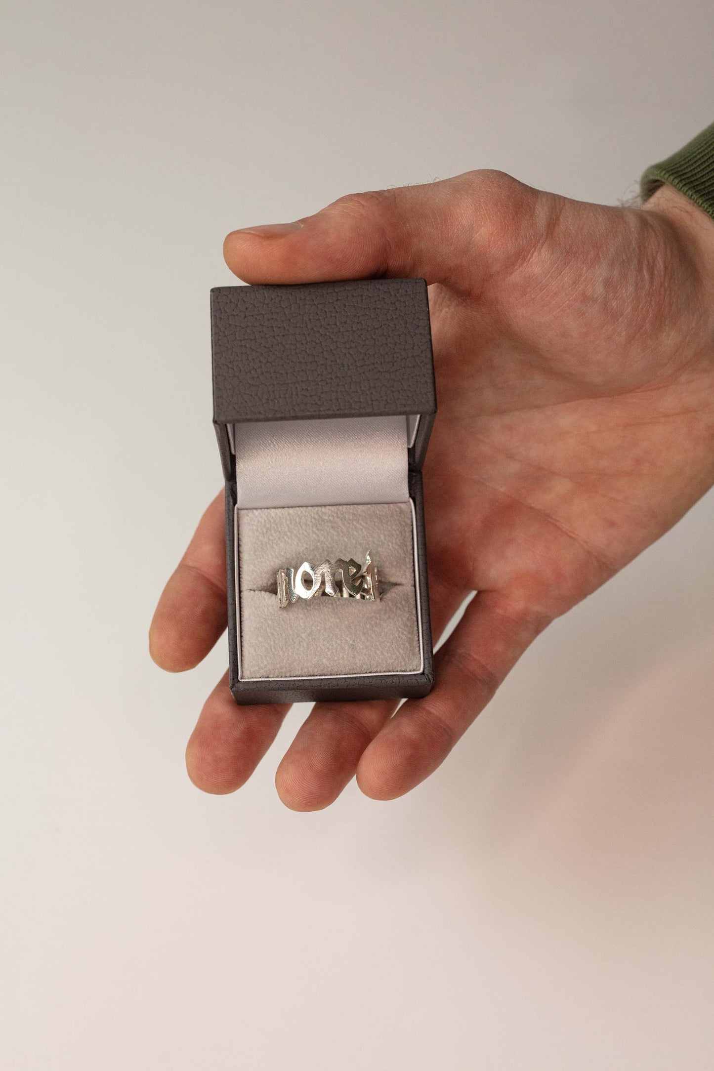 Sterling 925 silver ring engraved with 'more is more,' displayed in an open jewelry box held in a hand.