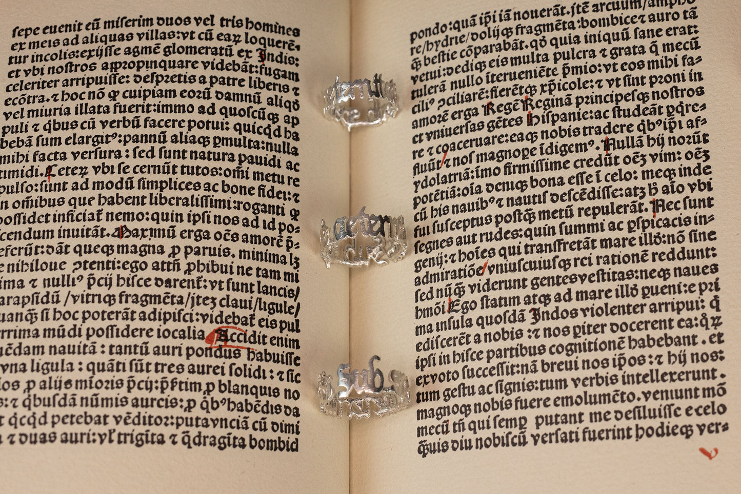Three sterling 925 silver rings engraved with 'sub specie aeternitatis,' placed on an open book with intricate blackletter font in the background.
