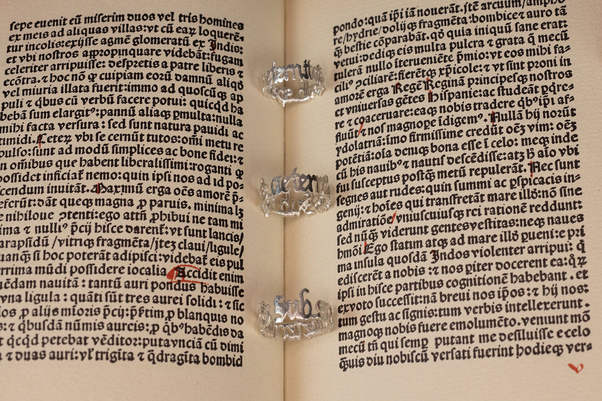 Three sterling 925 silver rings engraved with 'sub specie aeternitatis,' placed on an open book with intricate blackletter font in the background.
